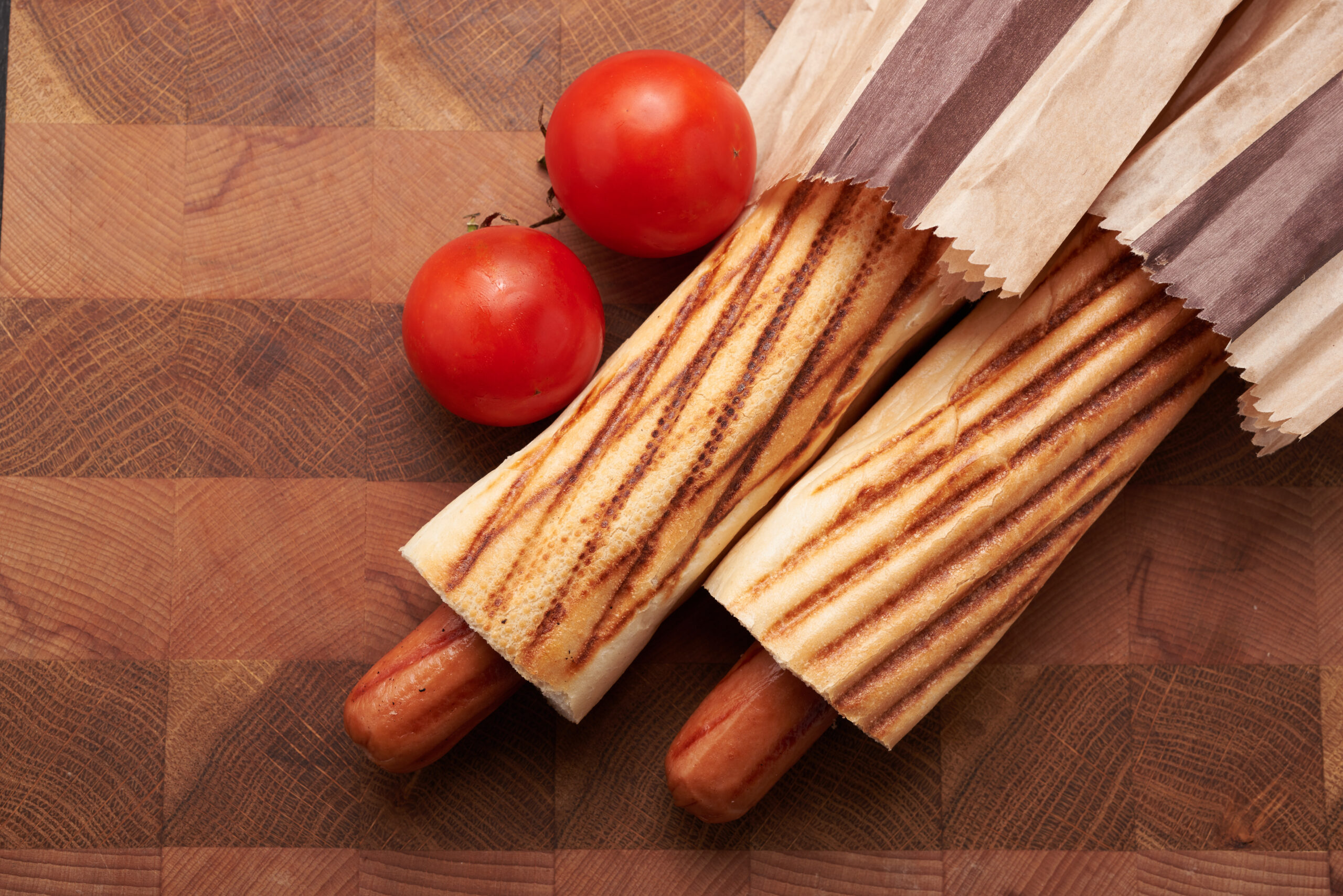 Two Hot Dogs And Tomato On A Table